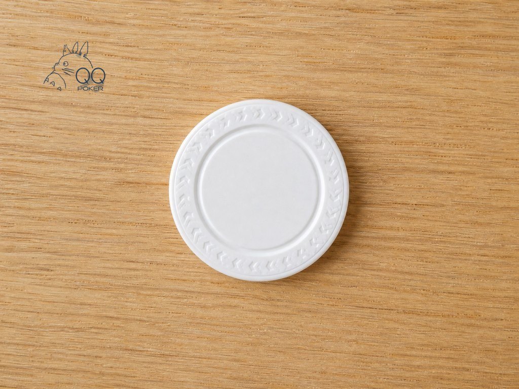 温暖浅橡木桌面上一枚白色圆形塑料庄家按钮,边缘压印花纹与中心凹槽清晰